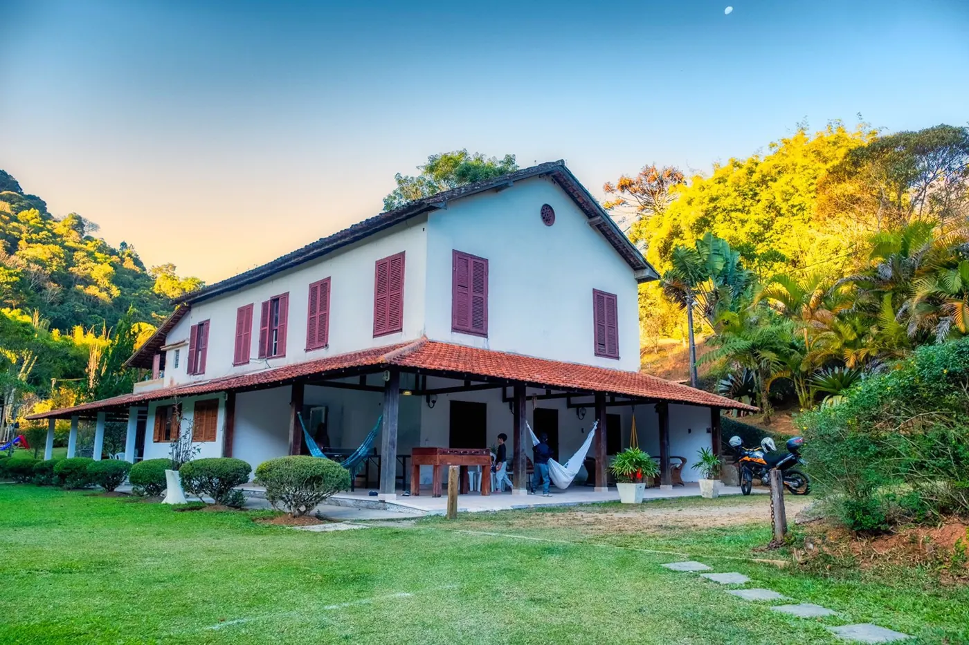 Casa do sítio ao entardecer, com varanda e gramado